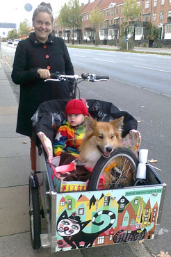 Et barn og en hund sidder begge i Louise Shonemanns ladcykel